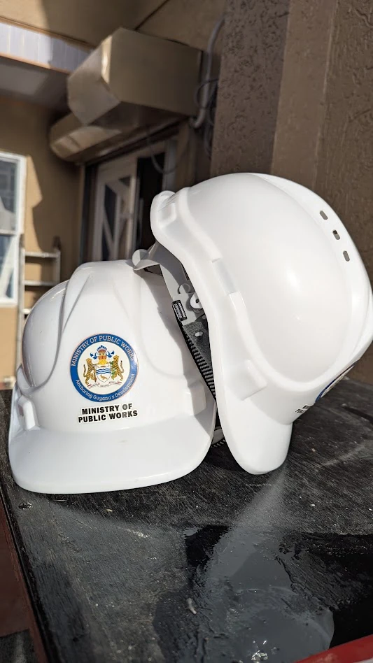 White hard hats branded with the Ministry of Public Works logo