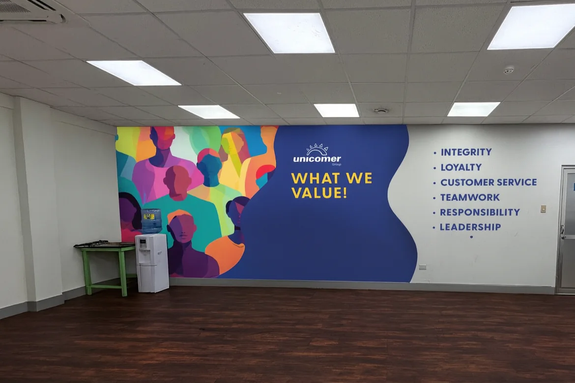 Unicomer corporate values graphic installed on an office wall